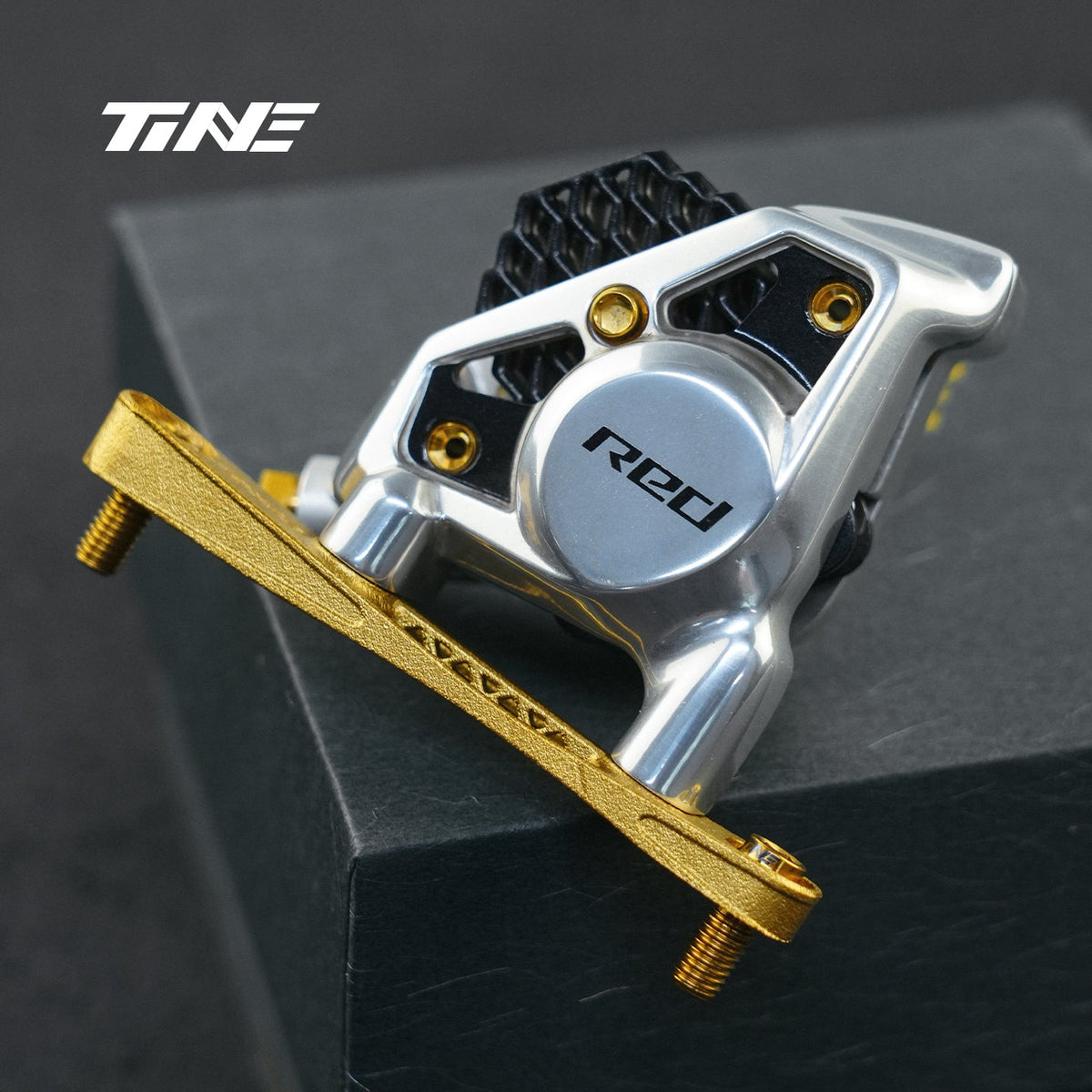 Soporte de freno delantero TiNE dorado montado en una pinza SRAM Red