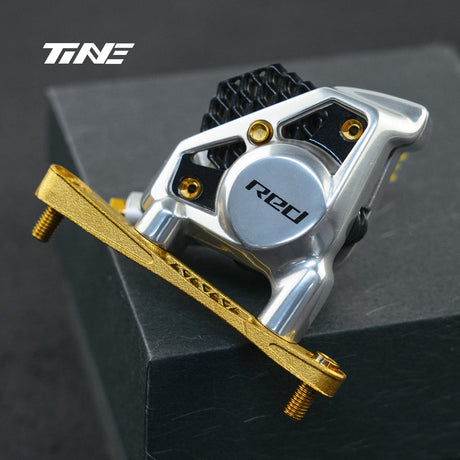 Soporte de freno delantero TiNE dorado montado en una pinza SRAM Red