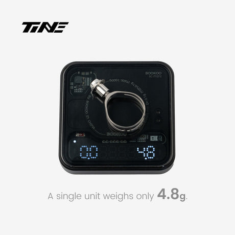 Abrazadera de manetas TiNE de titanio sobre una báscula que marca 4,8 g