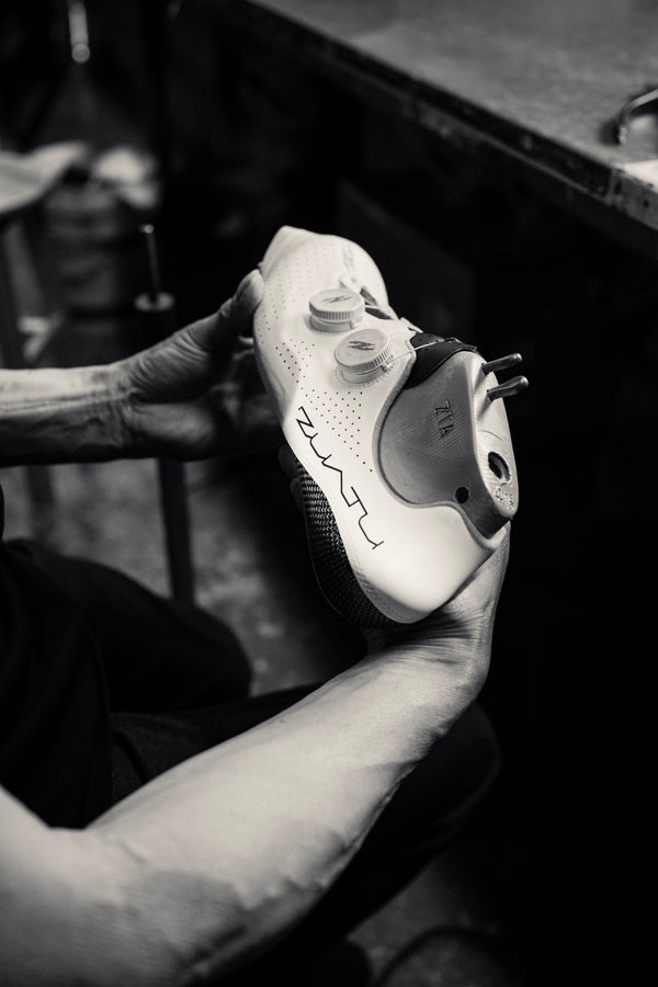 Hands holding a Zuatu cycling shoe